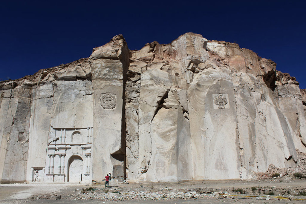 Grote rotswand met uitgehakte reliëfs en een monumentale poort in Peru tijdens een 22-35ers groepsrondreis.