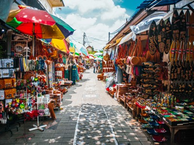Souvenirmarkt op Bali met kleurrijke parasols en kraampjes vol handwerk en houtsnijwerk.