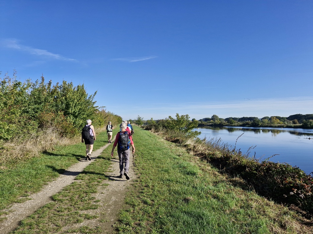 Wandelaars met rugzakken lopen over een pad langs de rivier tijdens de wandelvakantie Dutch Mountain Trail.