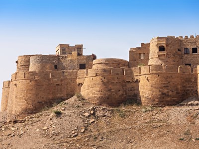 Zandstenen fort met ronde bastions en stadsmuur in Rajasthan, Noord-India, onder een heldere blauwe lucht.