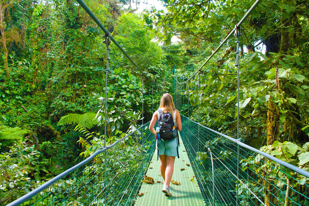 Rugzaktoerist loopt over hangbrug door het regenwoud tijdens 22-35ers reis Costa Rica.