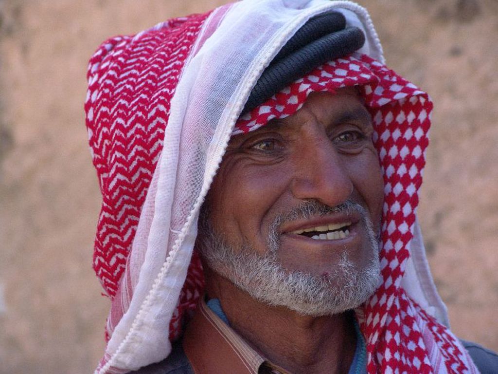 Portret van een Jordaanse man met rood-witte keffiyeh in de woestijn tijdens een familiereis Jordanië.