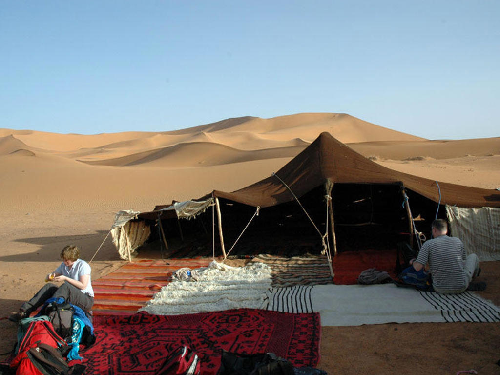 Tentenkamp in de Marokkaanse Sahara met zandduinen op de achtergrond tijdens groepsrondreis Marokko Totaal.