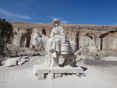 Beeld van een zoutmijnwerker op een ezel, uitgehouwen in zoutsteen bij de zoutmijnen van Maras in Peru.
