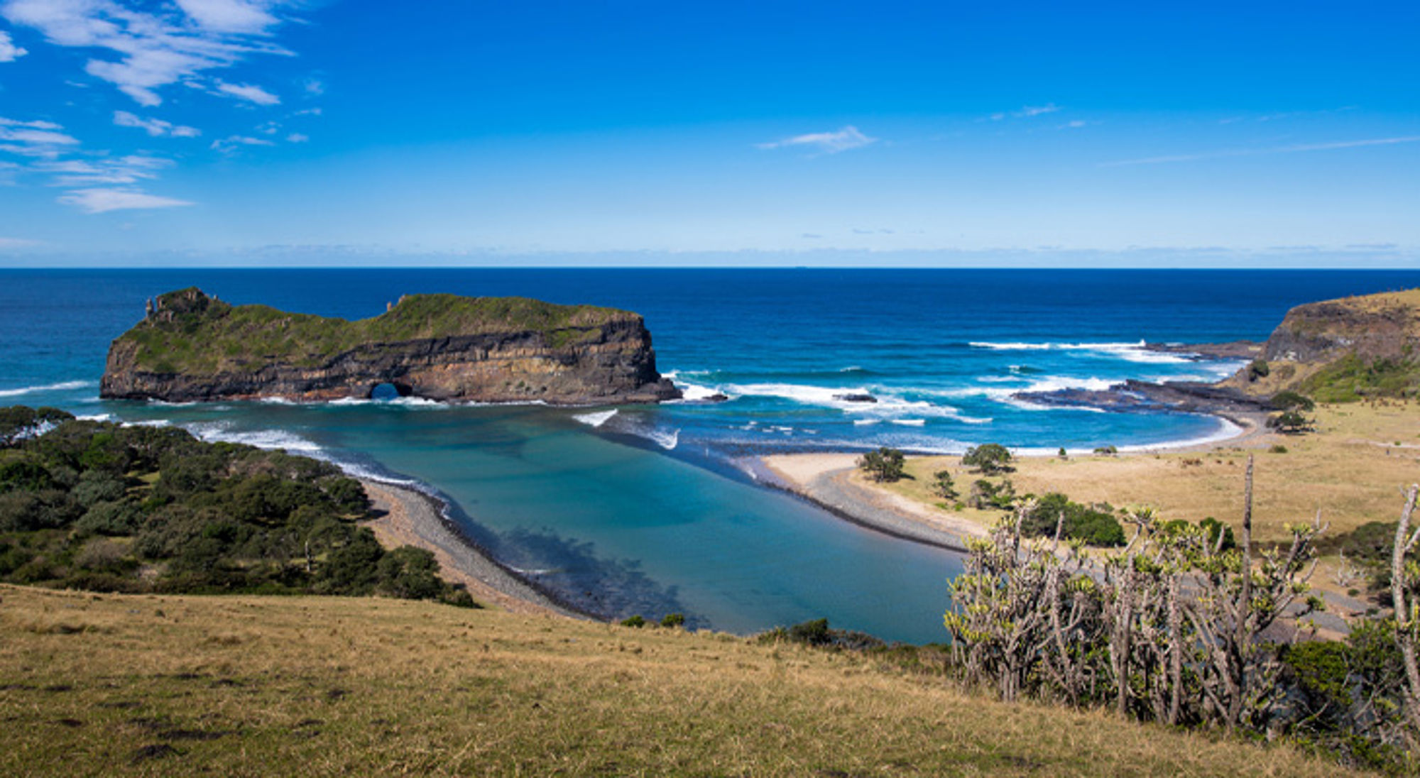 Coffee Bay Uitzicht op de kust van Zuid-Afrika met kliffen, blauwe lagune en golven bij een zandstrand.