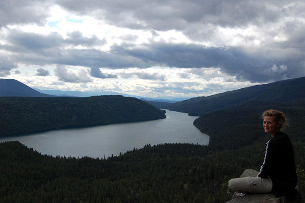 Reiziger op uitzichtpunt met panorama over rivier en beboste bergen in Canada West tijdens hotelrondreis.