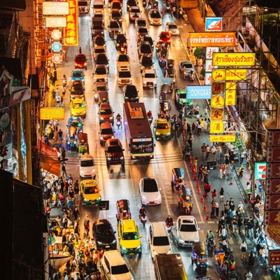 Drukke straat in Bangkok met neonreclames, verkeer en markten in de avond, tijdens groepsrondreis Thailand Hoogtepunten.