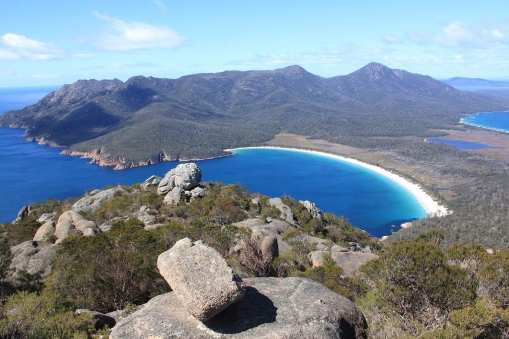 Uitzicht op Wineglass Bay in Tasmanië tijdens groepsrondreis Australië, met witte zandbaai en bergen.