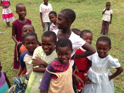 Groep lachende kinderen op een grasveld tijdens de route door Zambia, Malawi en Tanzania.