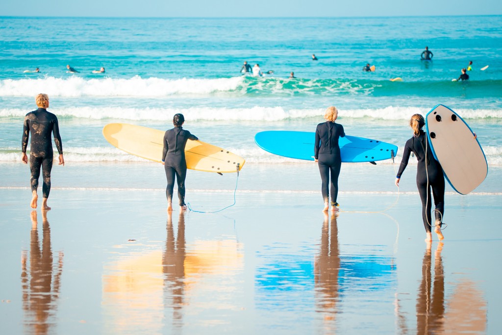 Surfers lopen met surfboards het strand op tijdens een 22-35ers reis Australië.