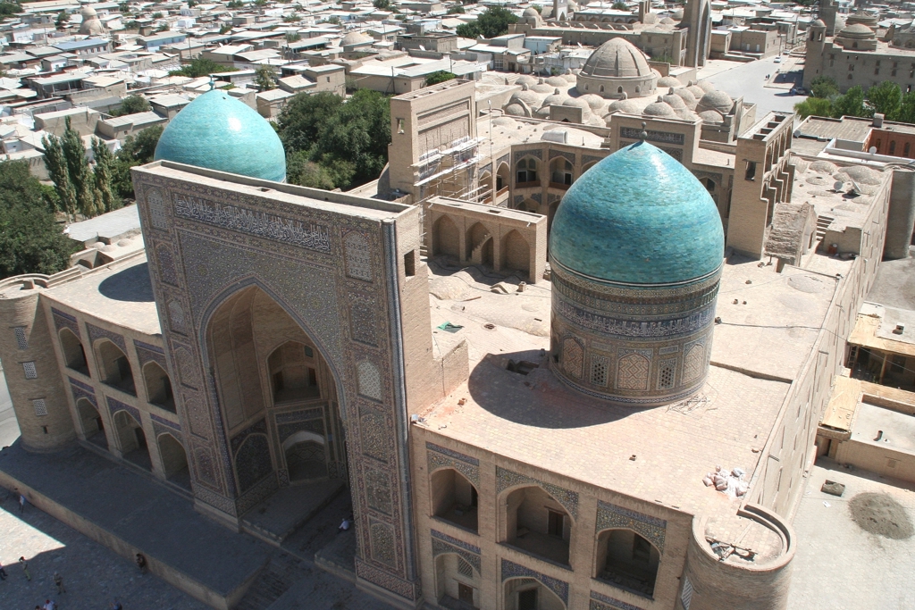 Blauwe koepels en mozaïekgevel van een historisch madrasa-complex langs de Zijderoute in Centraal-Azië.