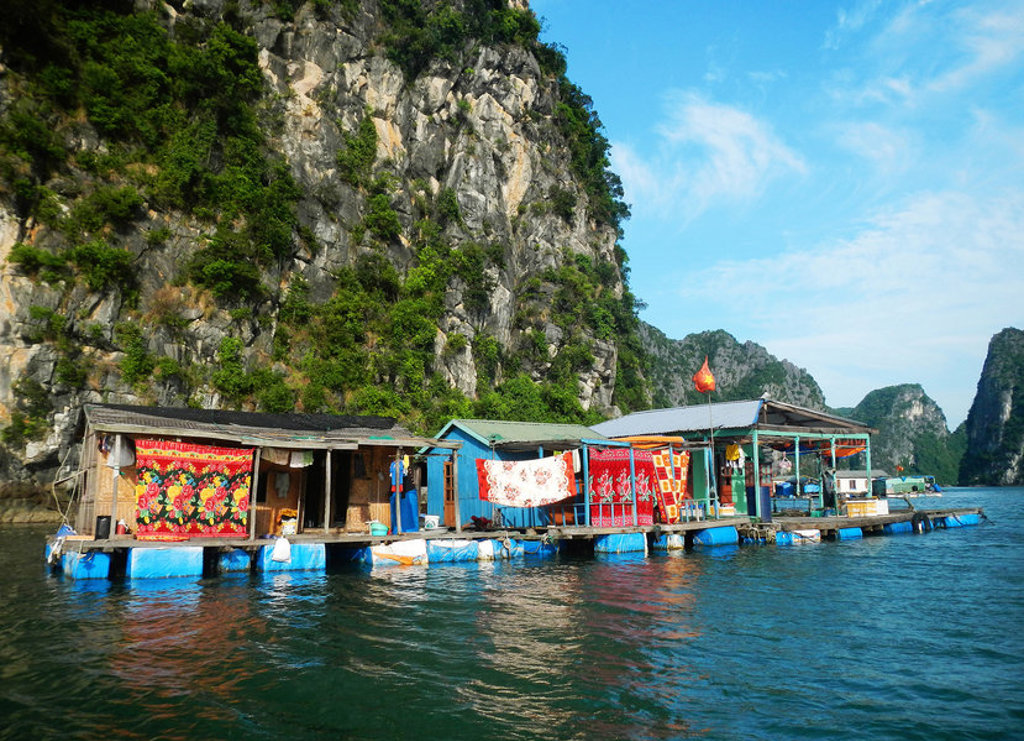 Drijvende huizen en vissersdorp op het water bij kalksteenrotsen in Laos, tijdens groepsrondreis Laos en Cambodja.