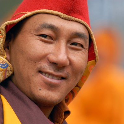 Portret van een boeddhistische monnik in Sikkim of Bhutan, met rode muts en traditionele kleding.
