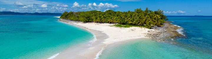 Wit zandstrand en palmbomen aan de turquoise lagune bij Nosy Be, Madagaskar.