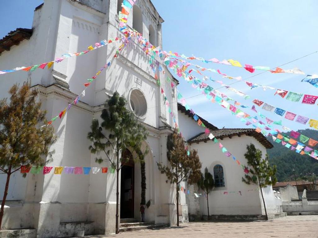 Witte kerk in Mexico met kleurrijke vlaggetjes boven het plein tijdens een familiereis door Mexico.