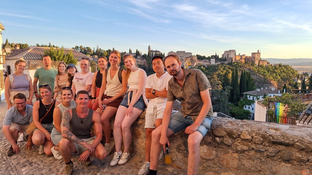 22-35ers groepsrondreis Andalusië met reizigers bij uitzichtpunt op het Alhambra in Granada tijdens zonsondergang.