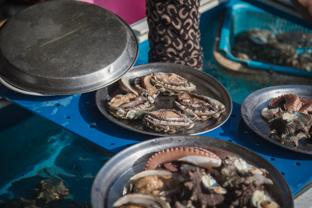 Verse zeevruchten op metalen schalen bij een vismarkt in Zuid-Korea.
