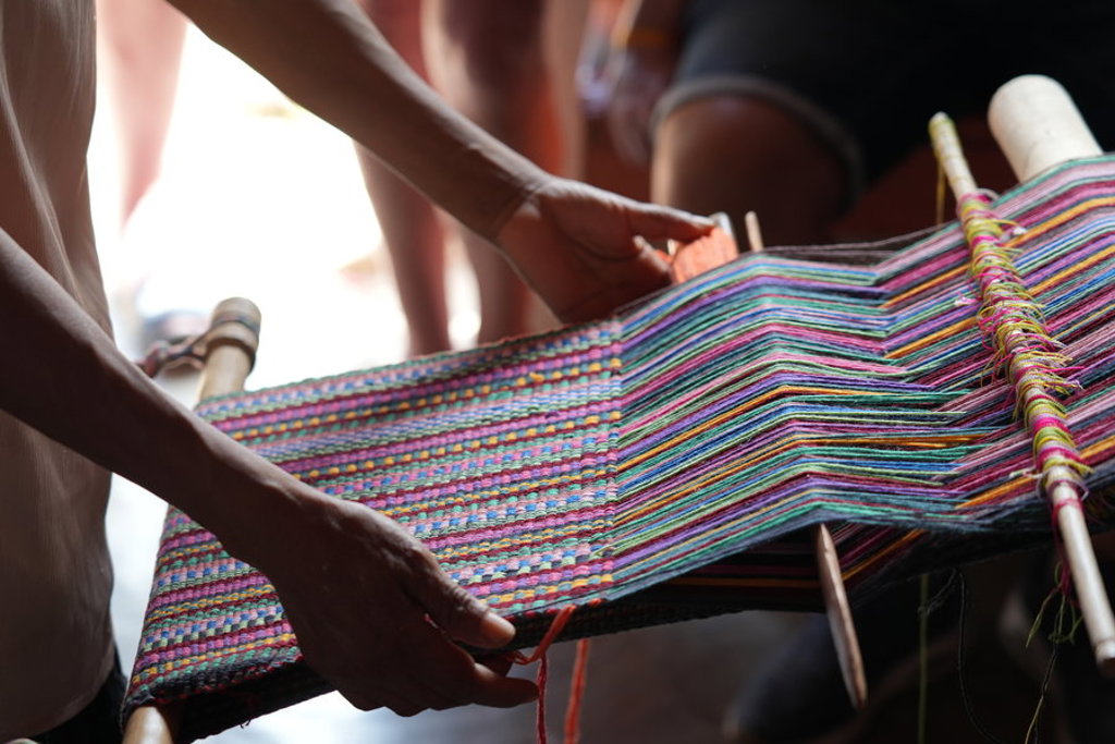 Handen weven kleurrijk textiel op een weefgetouw tijdens groepsrondreis Nicaragua en Costa Rica.