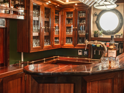 Houten bar met glazen kastjes, biertap en ronde patrijspoort, aan boord van een schip in Antigua.